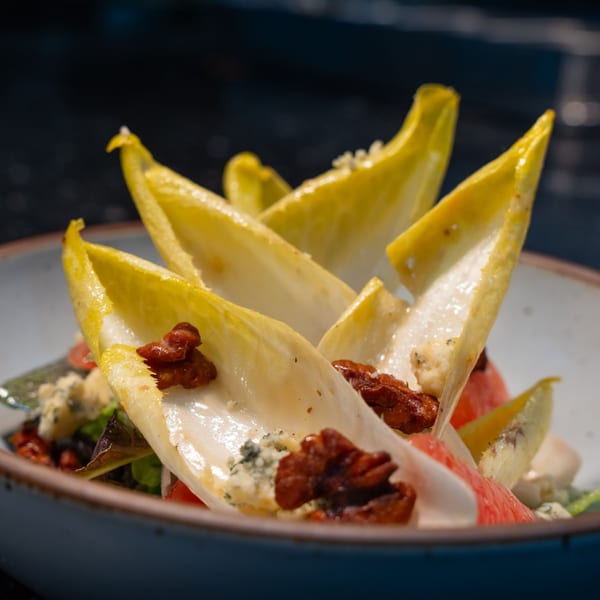 Ember's endive salad with candied walnuts, blue cheese, and grapefruit segments in a rustic bowl.