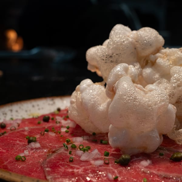 Close-up of Ember's beef carpaccio with capers, onions, chives, and crispy rice crackers.